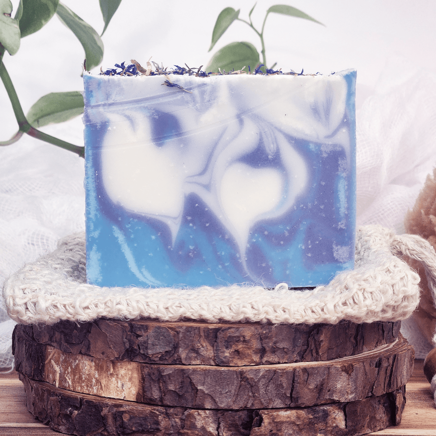 JOSSPURE blackberry sage mild shea butter soap bar with blue and white swirls on rustic wood display