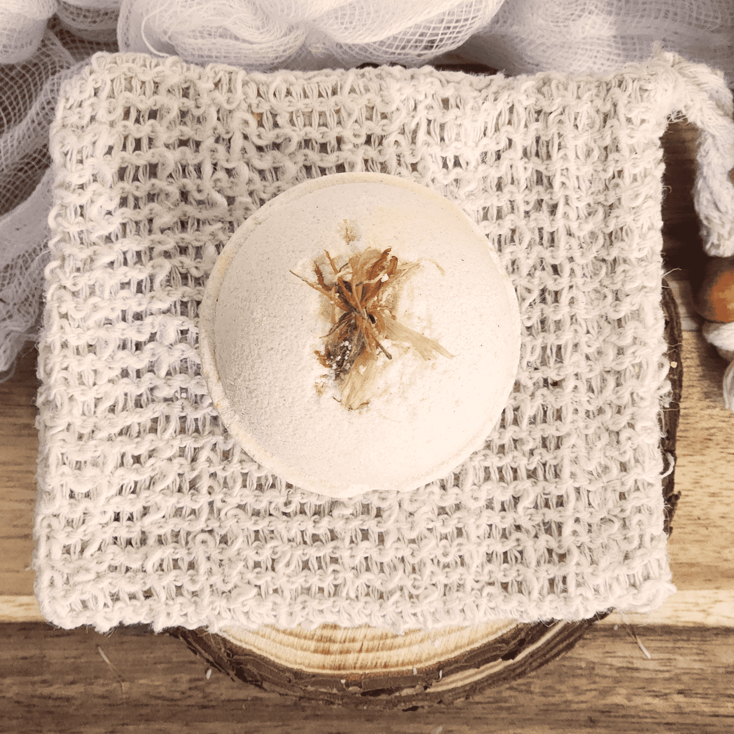 JOSSPURE grapefruit mini bath bomb with natural dried botanicals on a textured white cloth