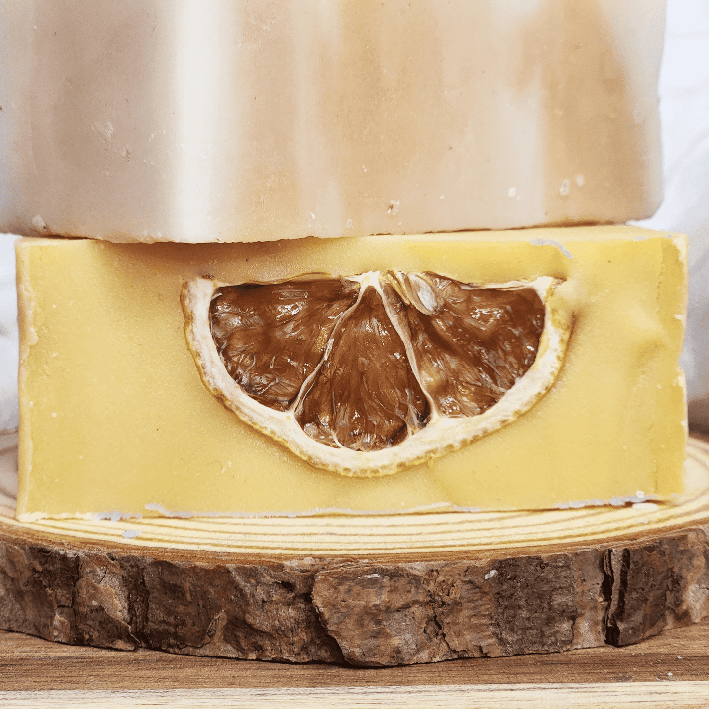 Handmade lemongrass mild shea butter soap bar with dried lemon slice on wooden display