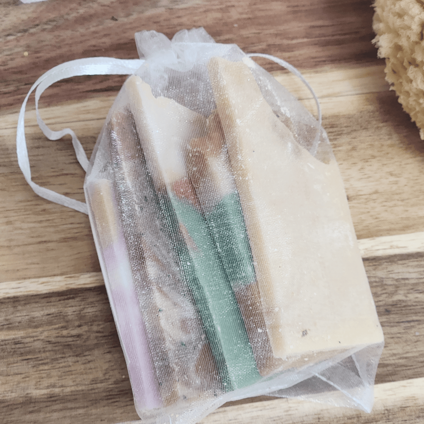 Artisan shea butter soap sampler with various natural handmade soap bars in a white mesh bag