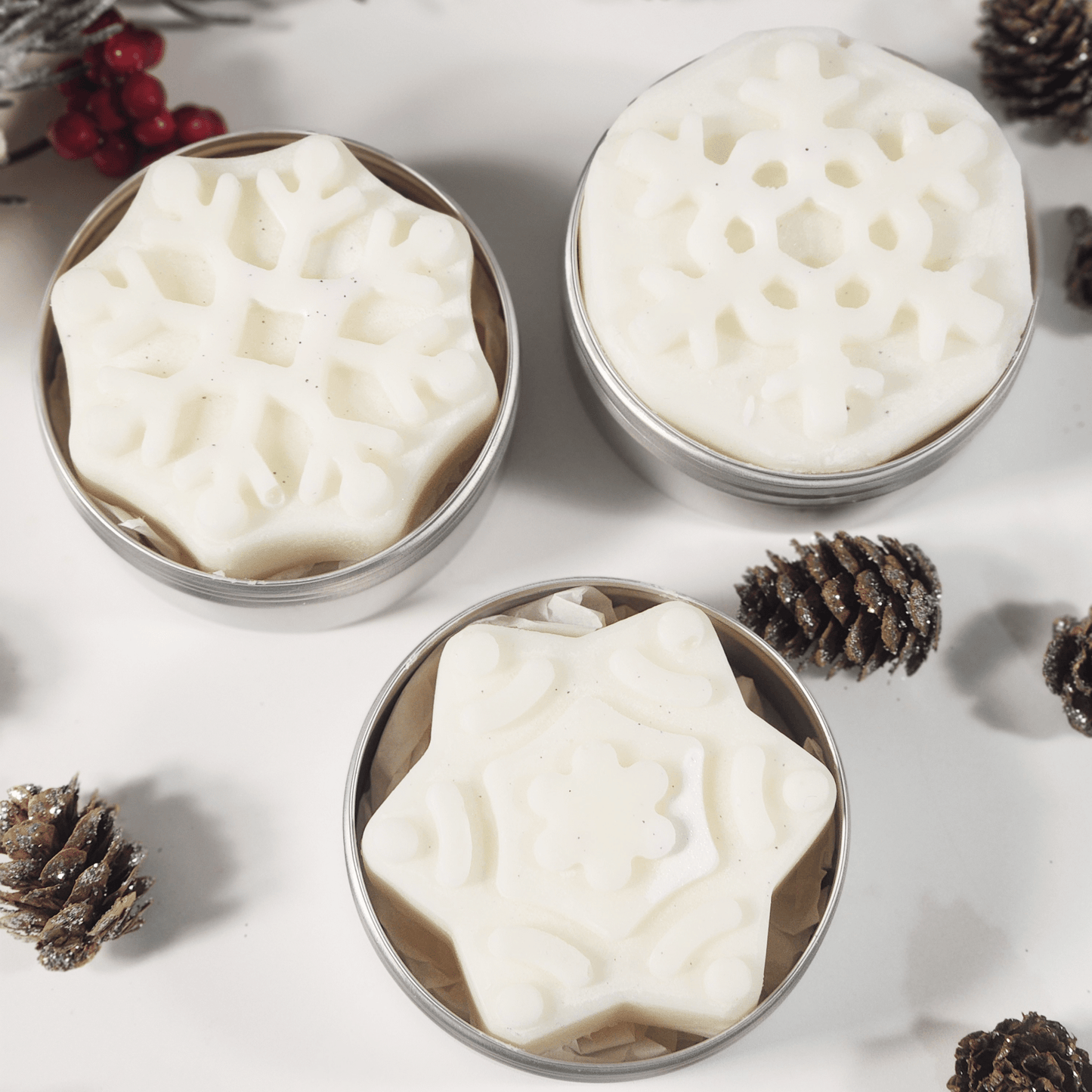 JOSSPURE handmade lotion bars shaped like snowflakes in metal tins with pine cones and holiday decor