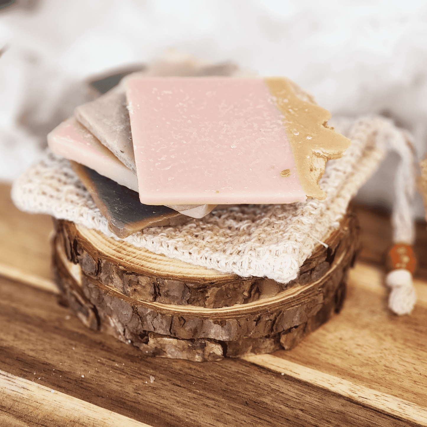 Handmade soap samples and sisal bag displayed on wooden round slices with natural textures