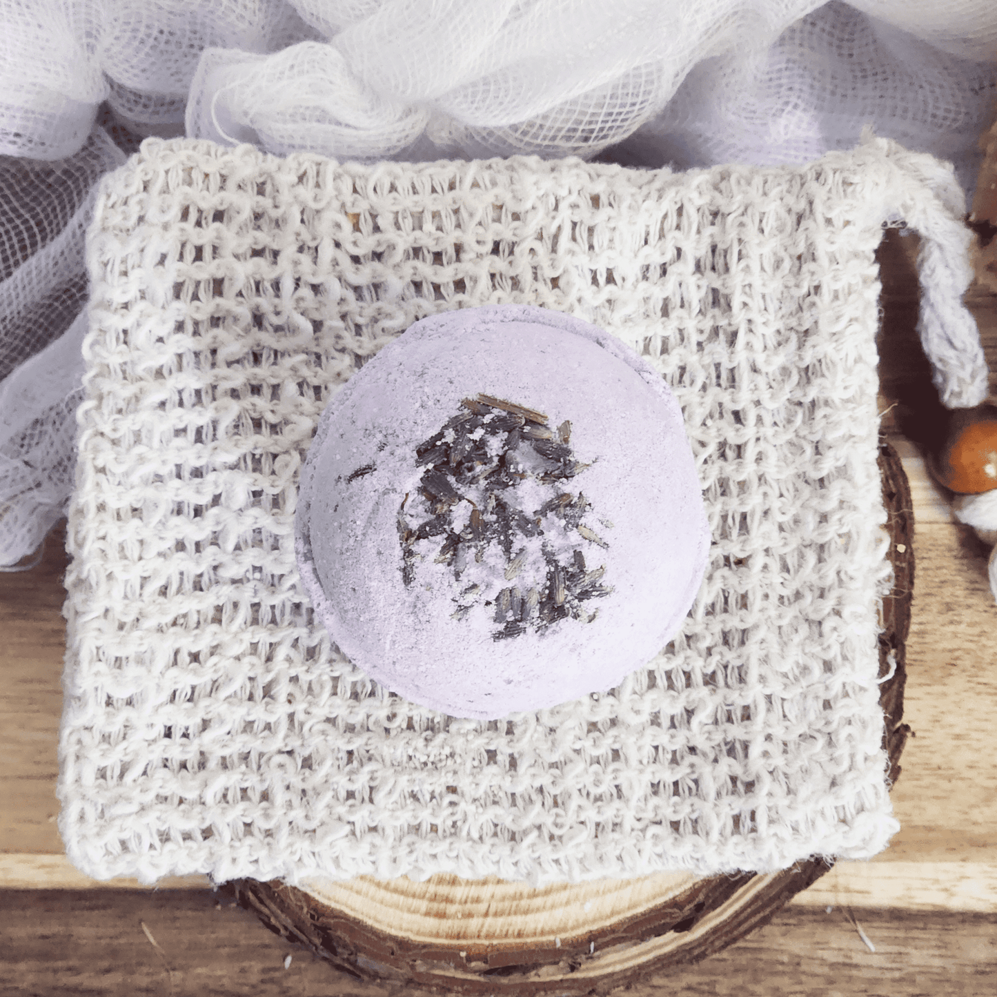 Lavender bath bomb with dried lavender petals on a woven white soap pouch by JOSSPURE