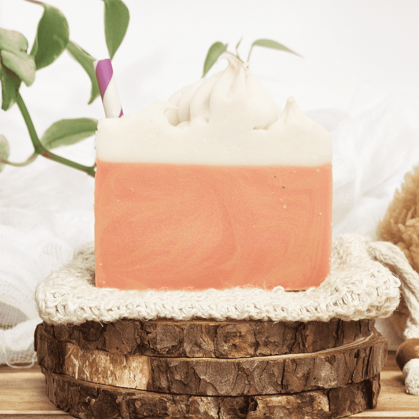 Handmade raspberry lemonade mild shea butter soap with creamy white top and orange base on natural wood background