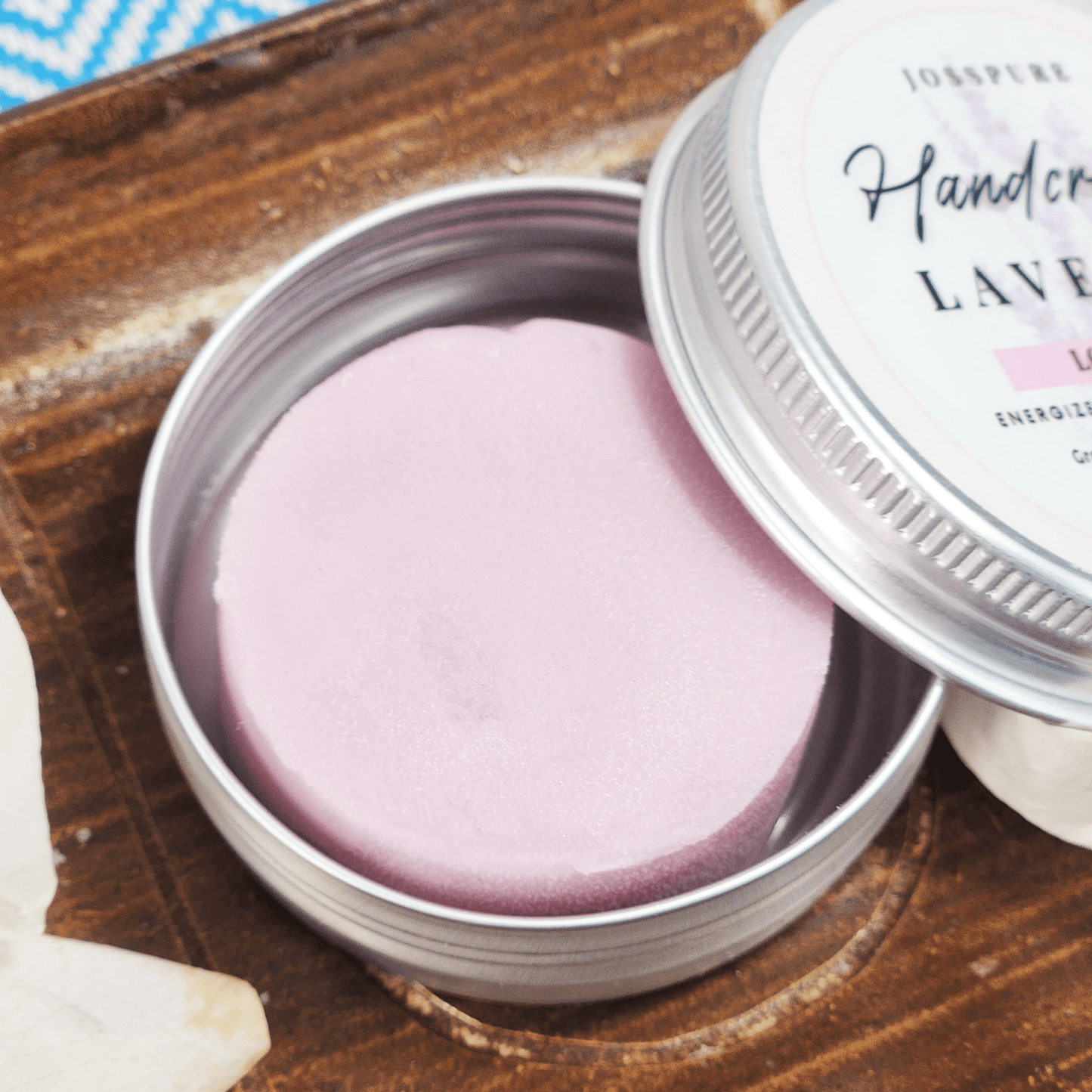 JOSSPURE lavender travel size mini lotion bar in a round metal tin on a wooden surface