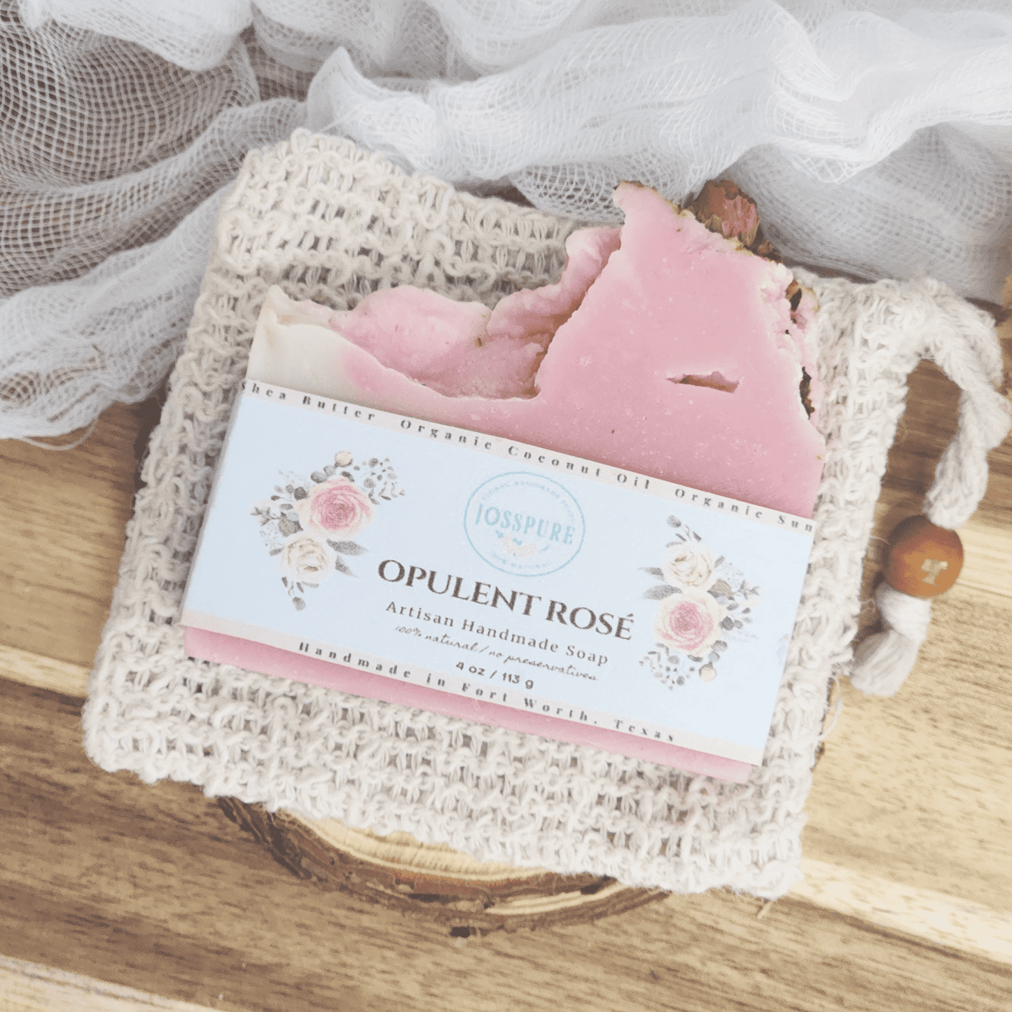 JOSSPURE rose mild shea butter soap bar wrapped in floral label on a woven soap pouch