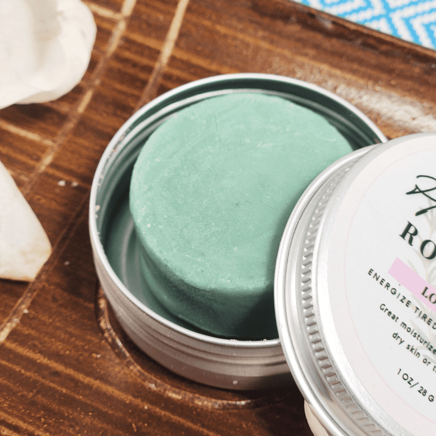 JOSSPURE rosemary travel size mini lotion bar in a round tin container on wooden surface