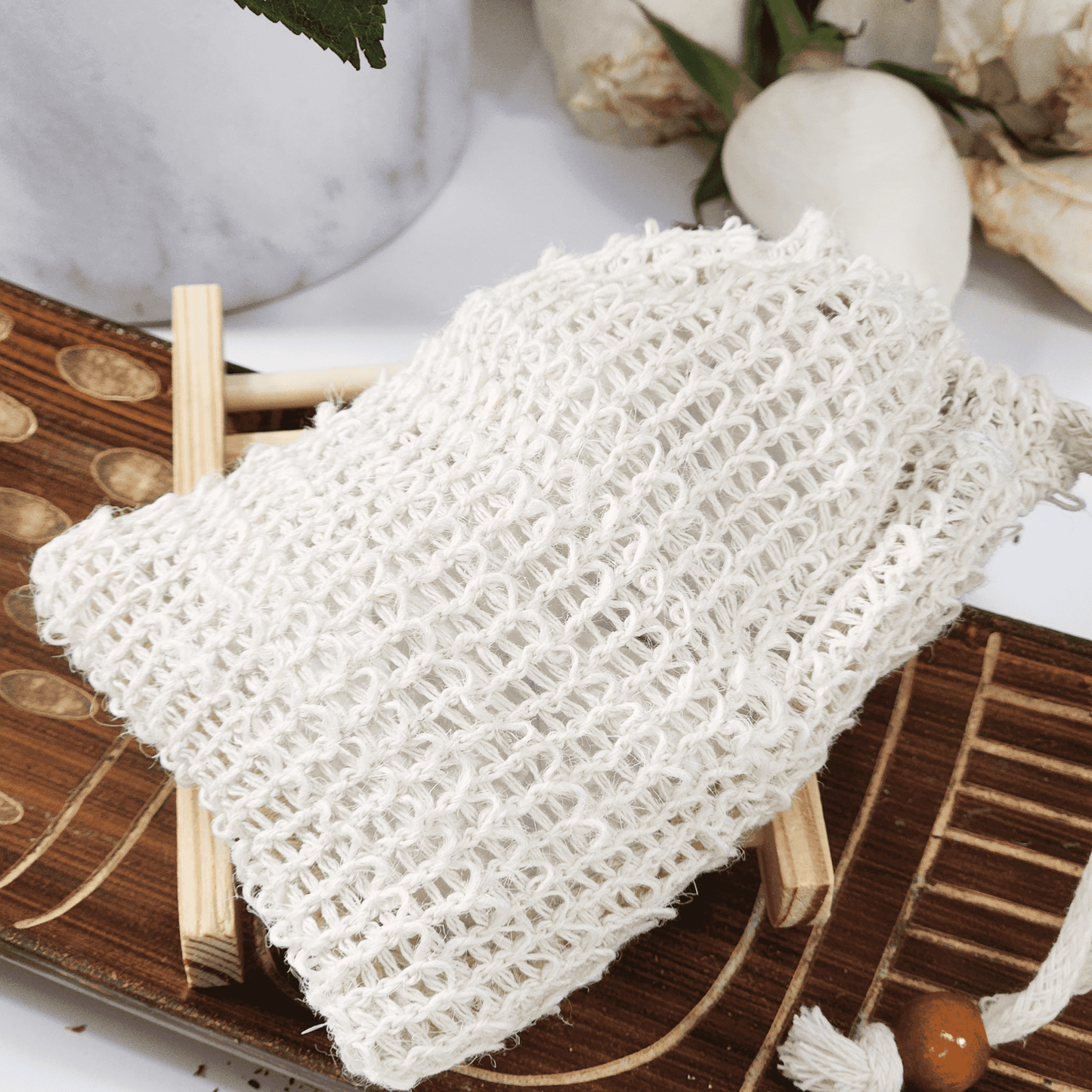 White soap saver and sisal bag for soap displayed on wooden soap dish with natural decor