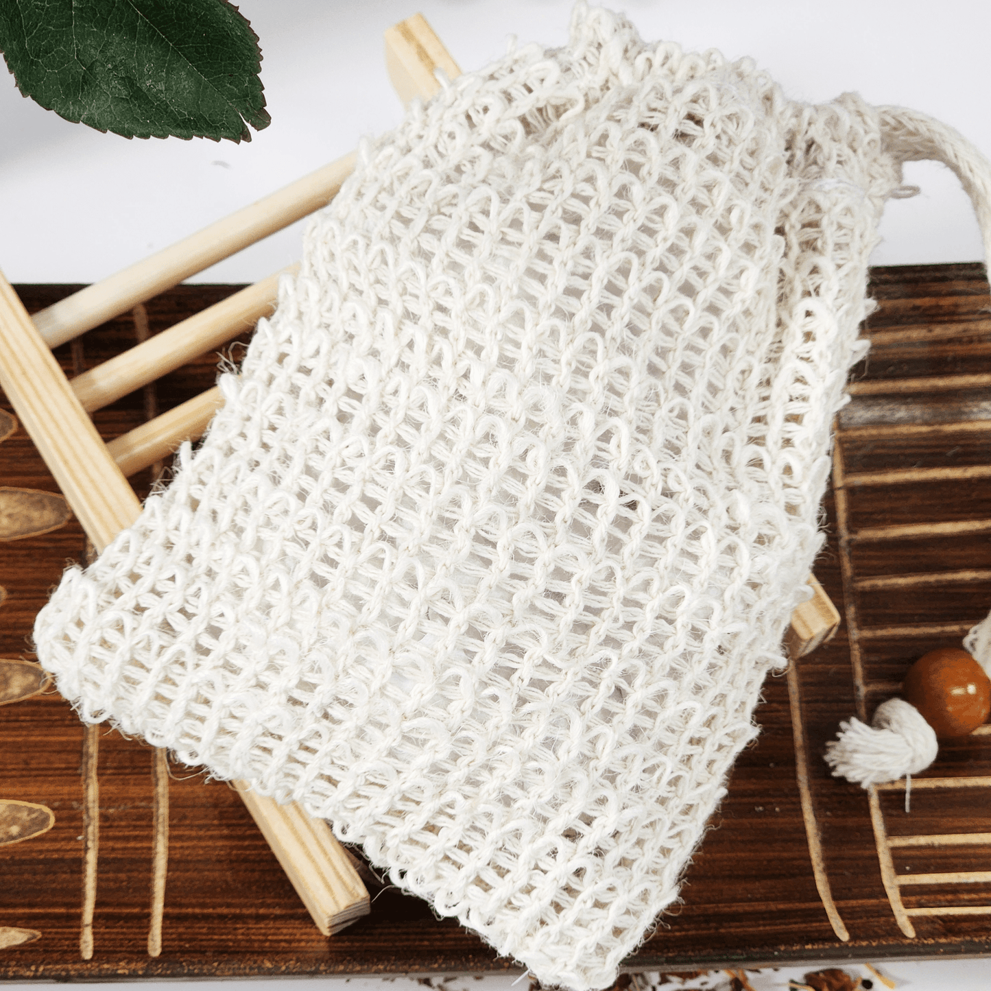 JOSSPURE soap saver and sisal bag for soap on wooden surface with green leaf background