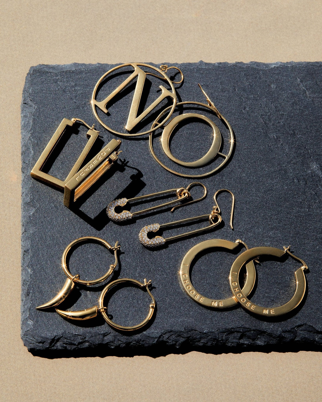 Assorted bold empowered jewelry featuring earrings and statement pieces on a textured surface
