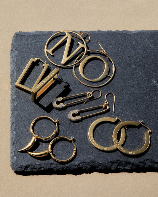 Assorted bold empowered jewelry featuring earrings and statement pieces on a textured surface