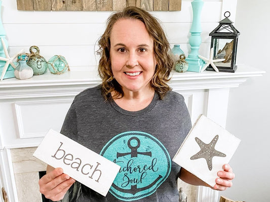 Woman holding sea anchored beach signs with coastal decor in a bright living room setting