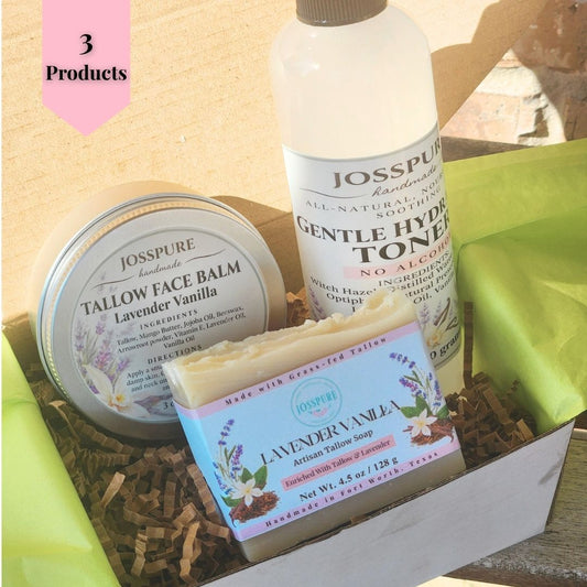 A JoSSPURE gift set containing lavender vanilla face balm, gentle hydralone toner, and artisan yellow soap, arranged in a box with brown paper shred and green tissue paper.