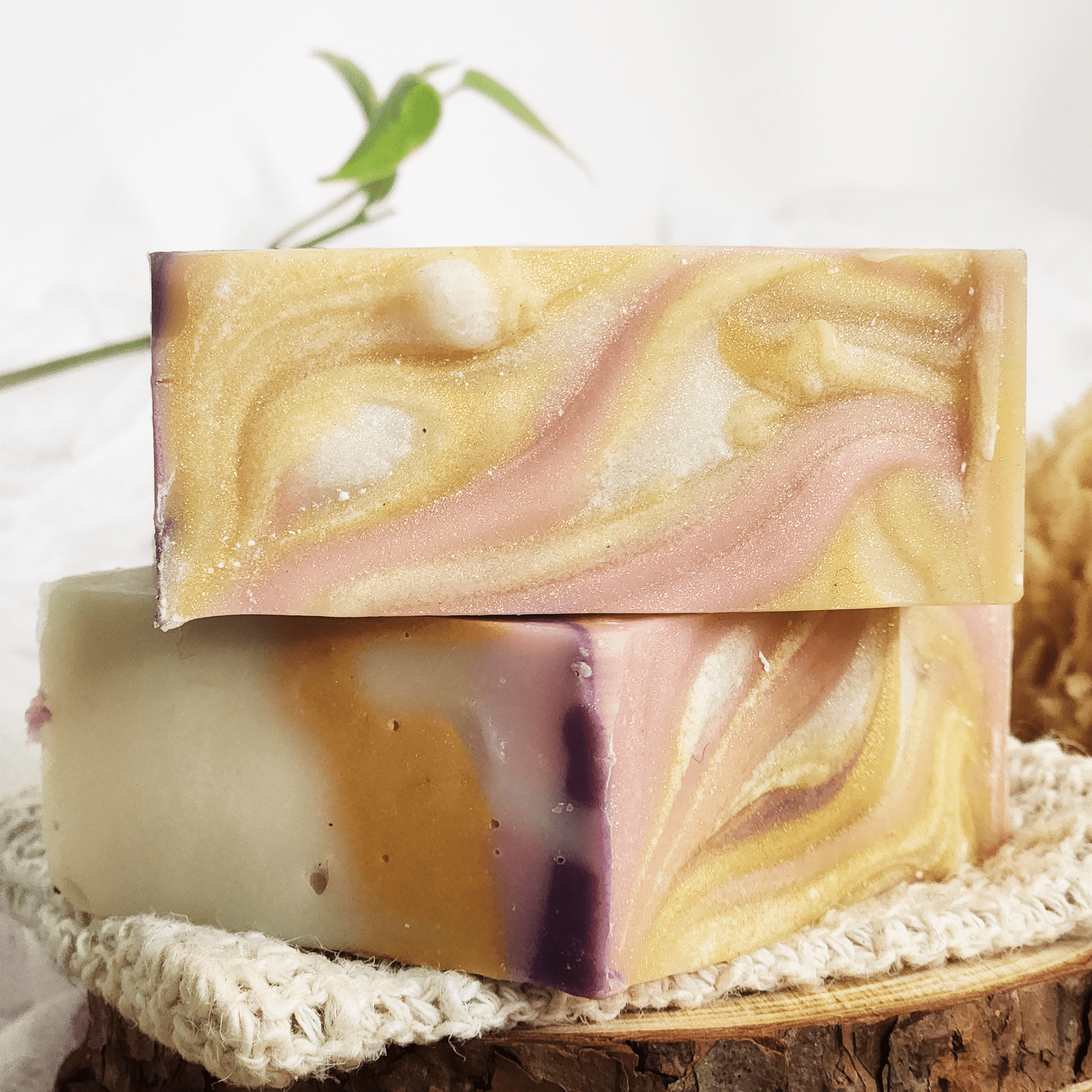 Black raspberry vanilla mild shea butter soap bars with swirled gold and pink colors stacked on knitted cloth