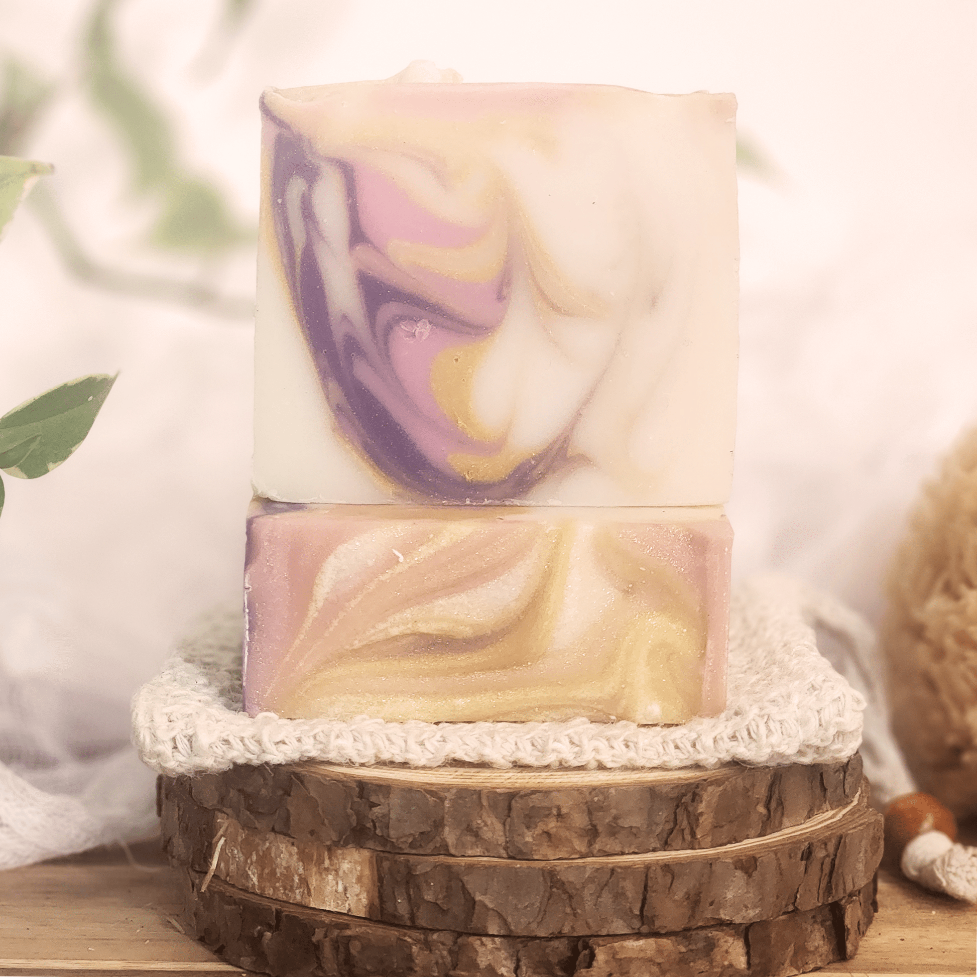 JOSSPURE black raspberry vanilla mild shea butter soap bars with swirled purple and gold design on natural wood and cloth background