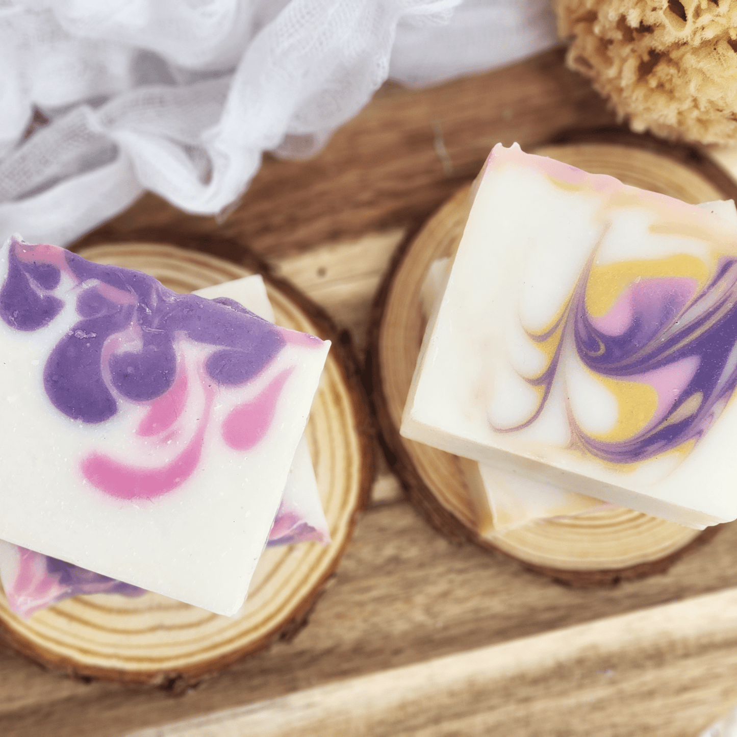 Handmade black raspberry vanilla mild shea butter soap bars with purple and pink swirls on wooden coasters