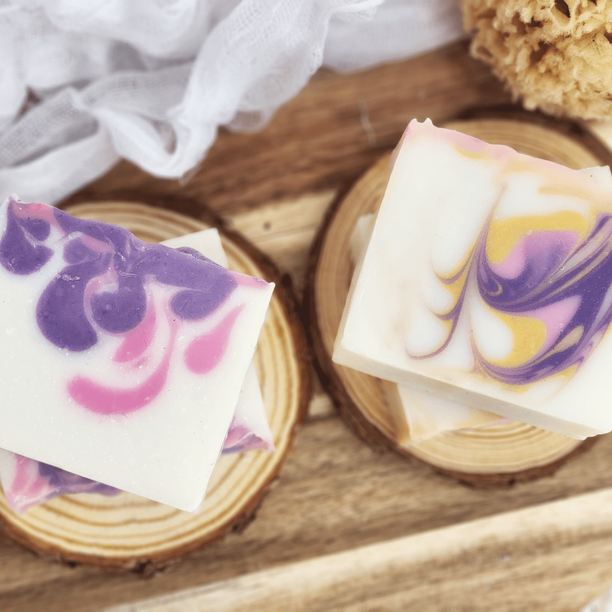 Handmade black raspberry vanilla mild shea butter soap bars with purple and pink swirls on wooden coasters