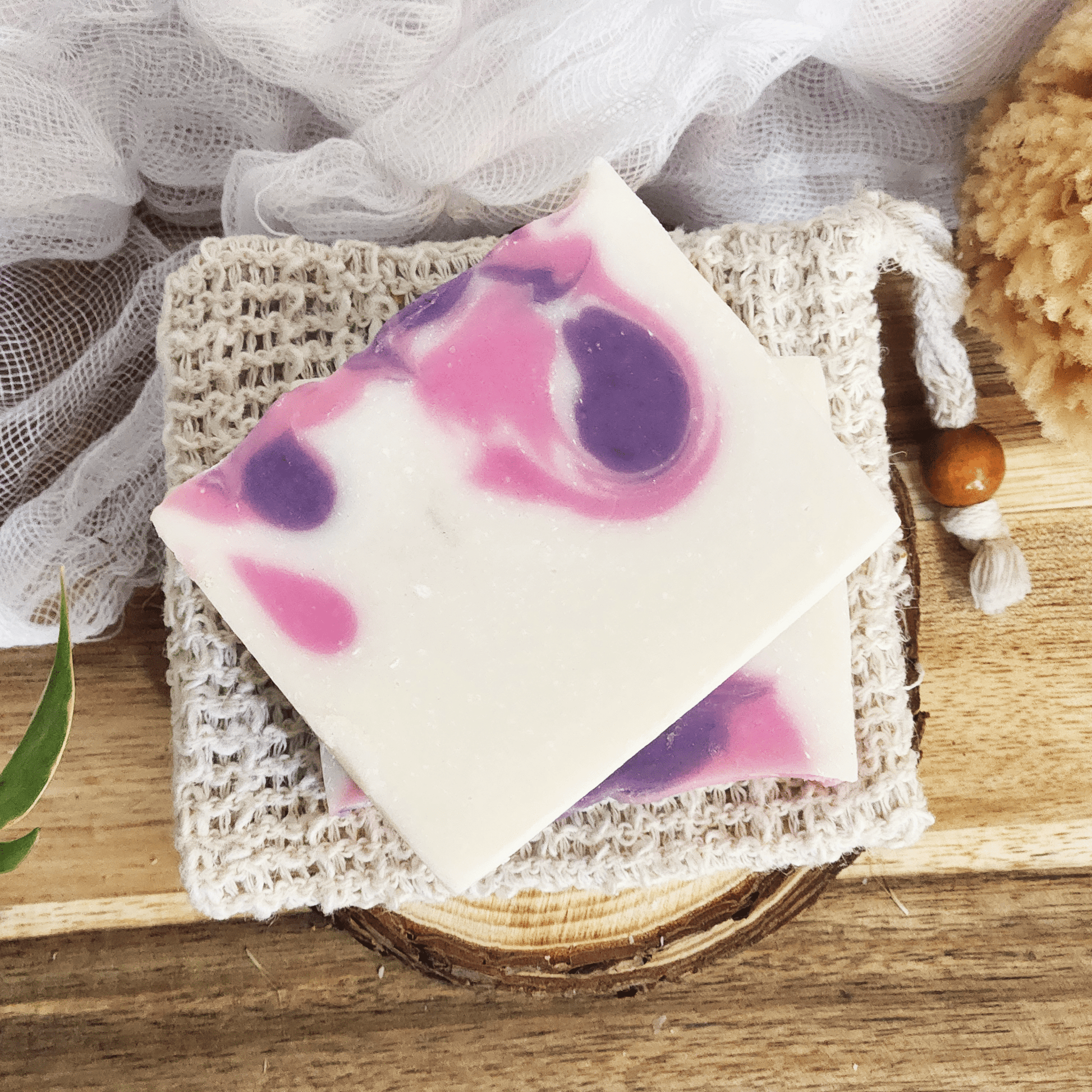 JOSSPURE black raspberry vanilla mild shea butter soap with purple and pink swirls on a natural soap saver