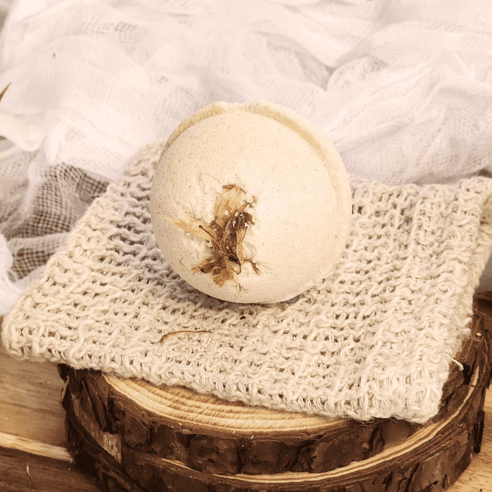 JOSSPURE grapefruit mini bath bomb resting on a textured beige cloth over a wooden surface