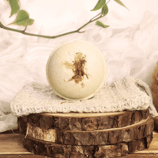 JOSSPURE grapefruit mini bath bomb with dried flower on top displayed on knitted cloth and wood slices