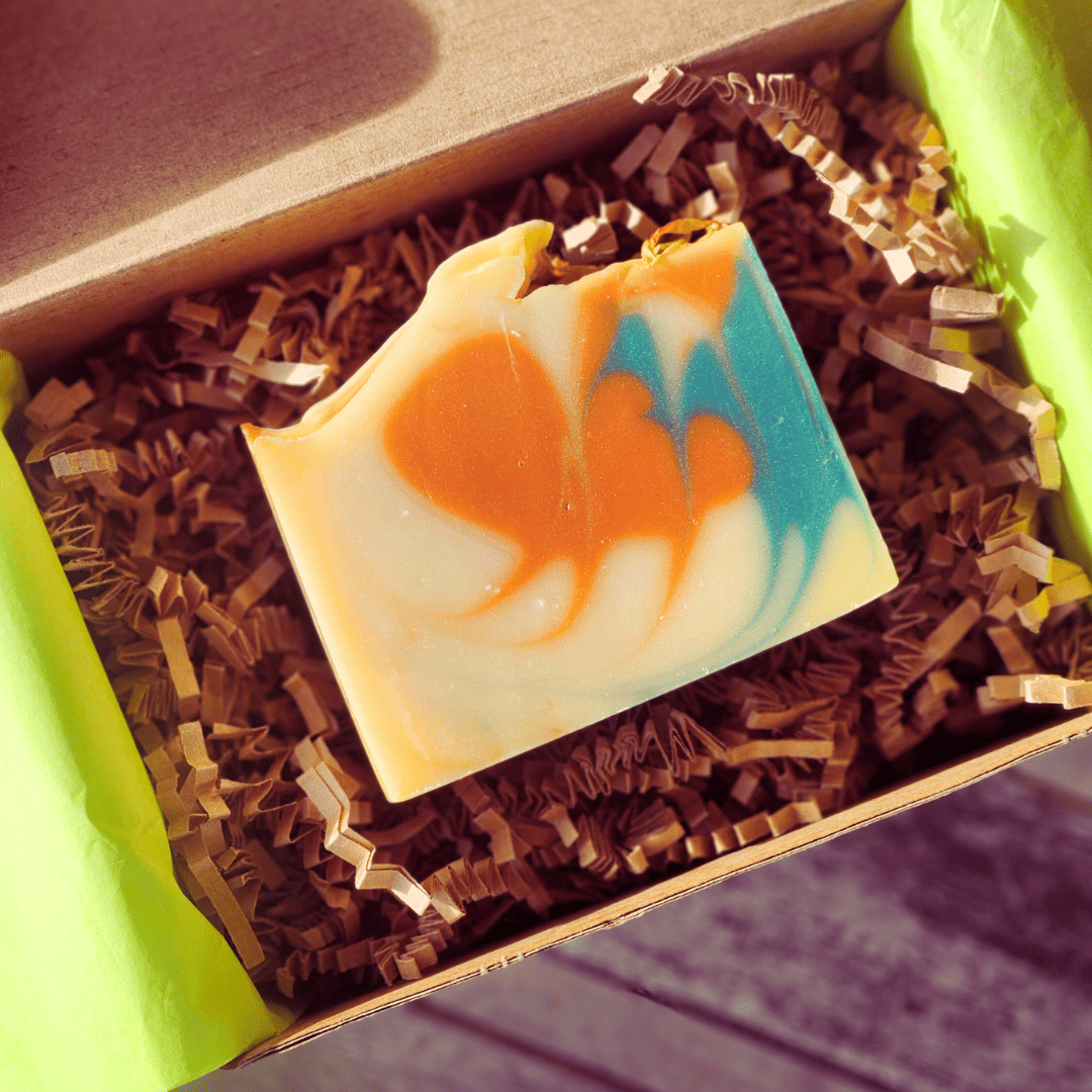 Colorful soap bar with orange and blue swirls in a brown box