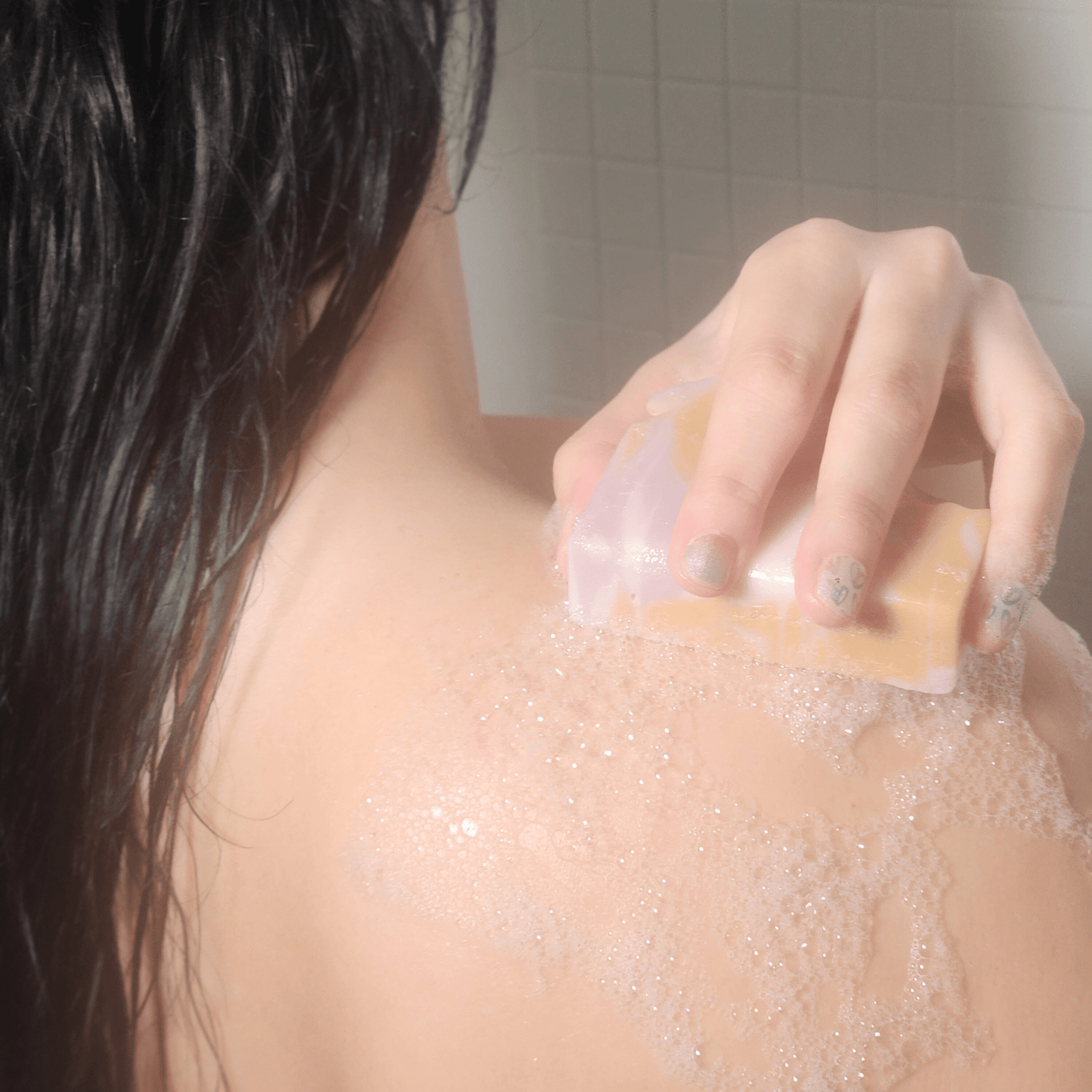 Person using Green All Natural Soap to lather and cleanse their wet back in the shower