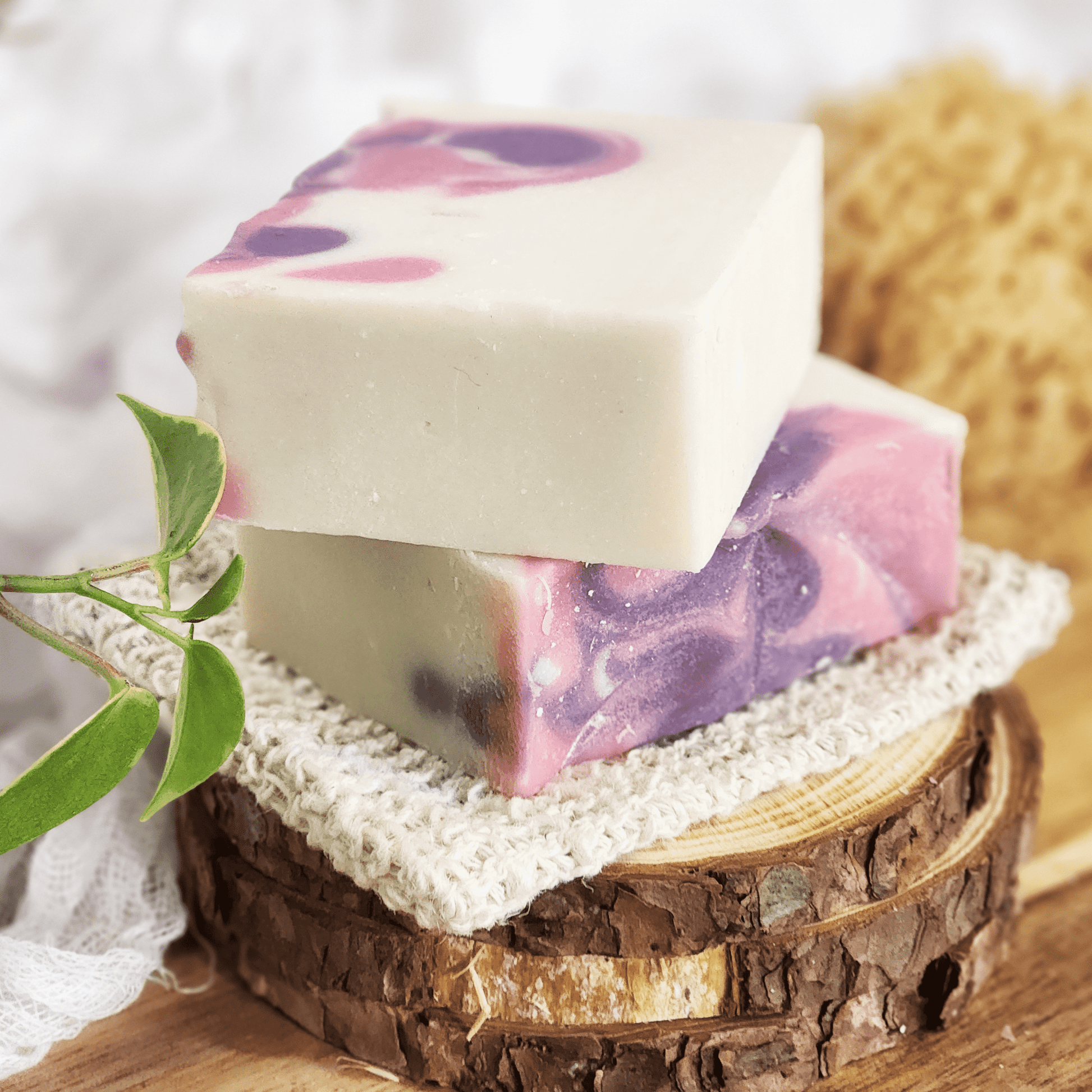 Black raspberry vanilla mild shea butter soap bars stacked on a wooden surface with natural decor