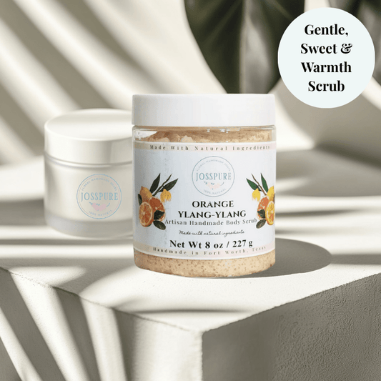 JOSSPURE orange ylang ylang sugar scrub in clear jar with white lid on textured white surface