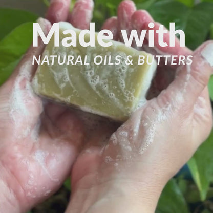 artisan soap bar in between hands with bubbles around it 