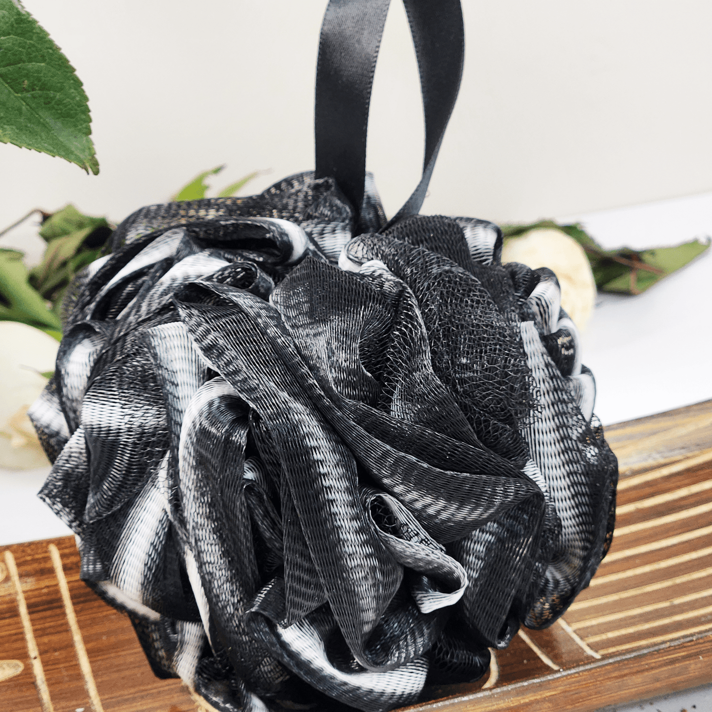 Black and white recycled eco friendly bath sponge with textured mesh and hanging ribbon