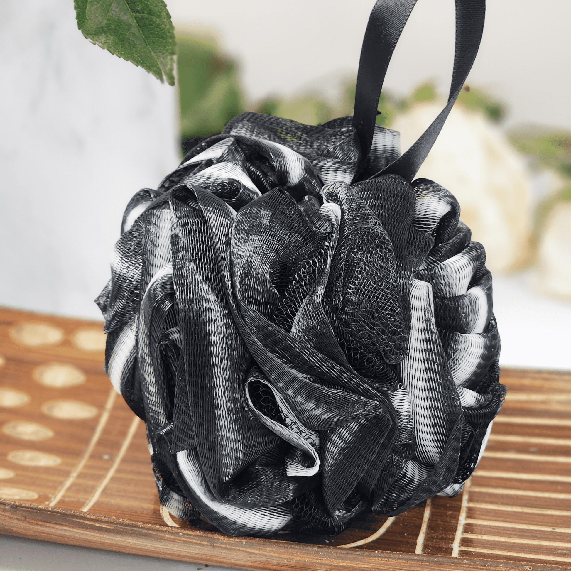 Black and white recycled eco friendly bath sponge hanging with ribbon on wooden surface