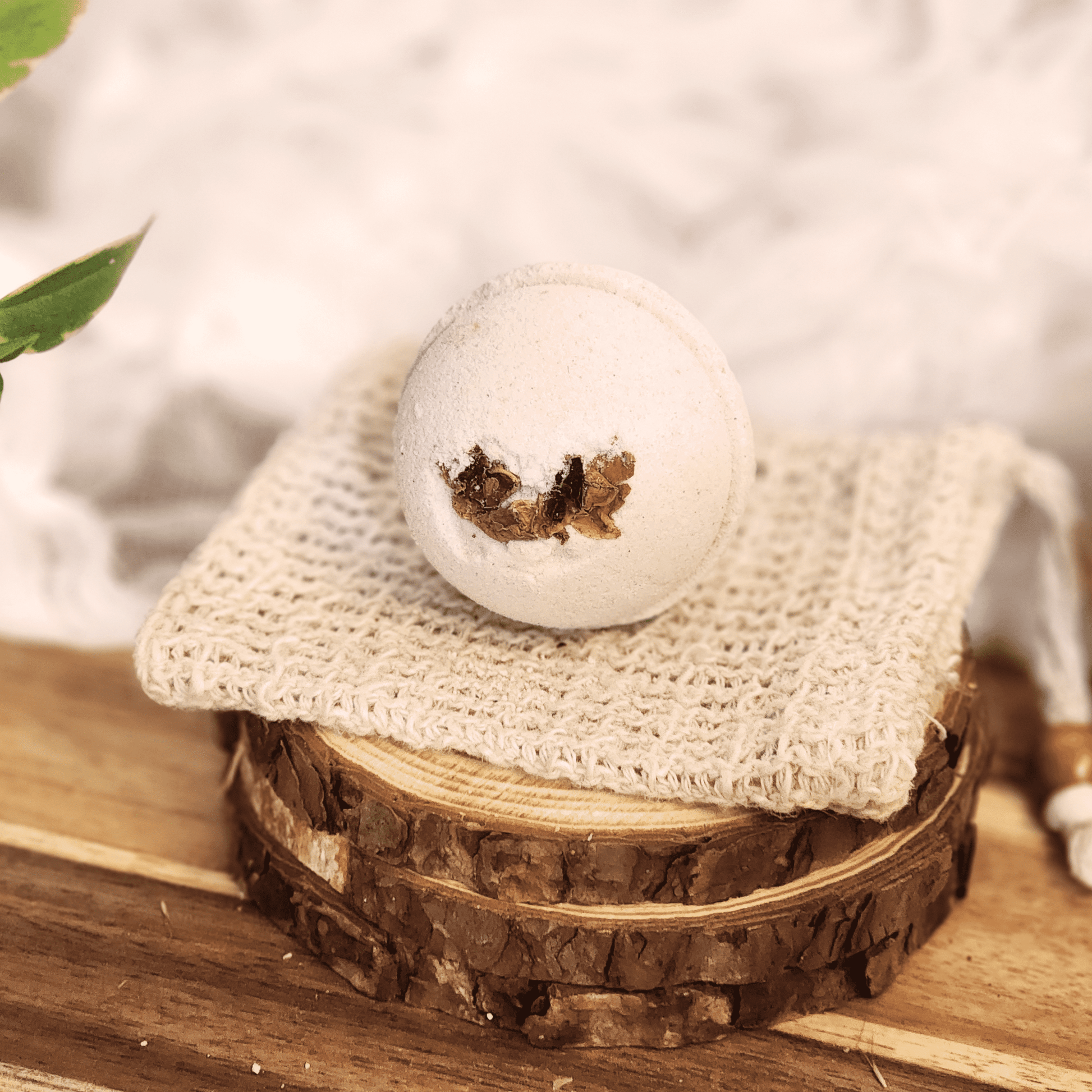 Rose luxury bath bomb with dried flower petals on natural textured cloth over wood slices