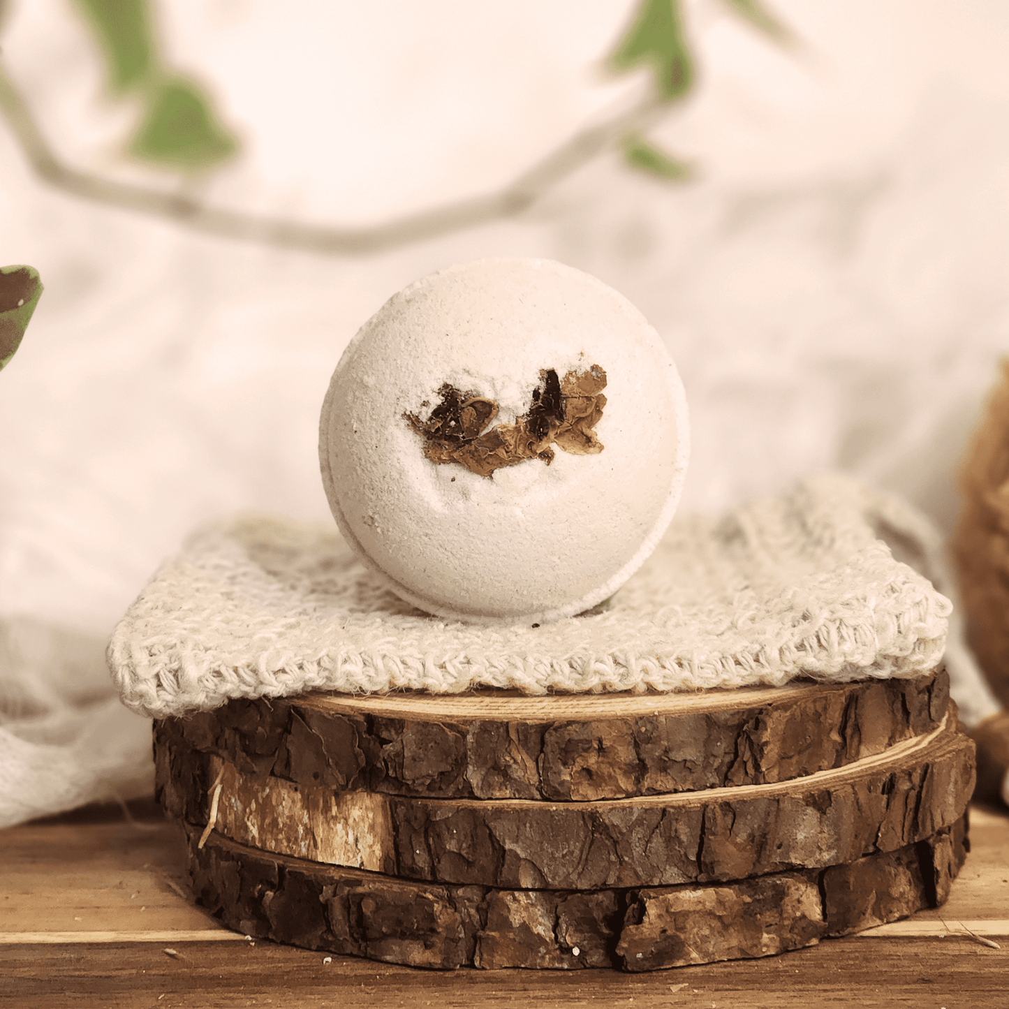 Rose luxury bath bomb with dried flower petals on a knitted cloth and wooden slices display
