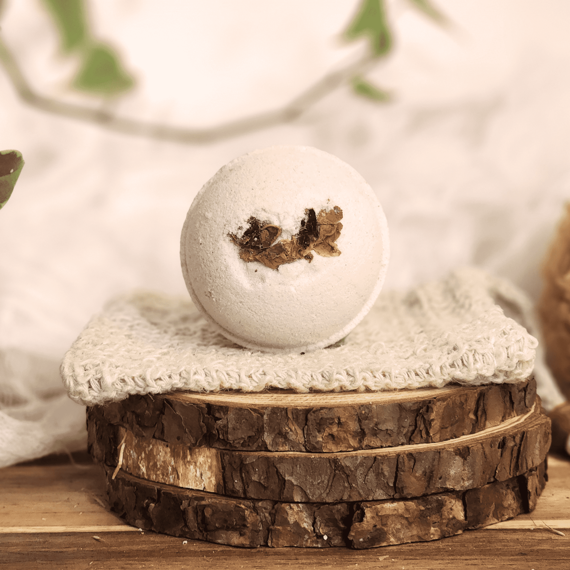 Rose luxury bath bomb with dried flower petals on a knitted cloth and wooden slices display