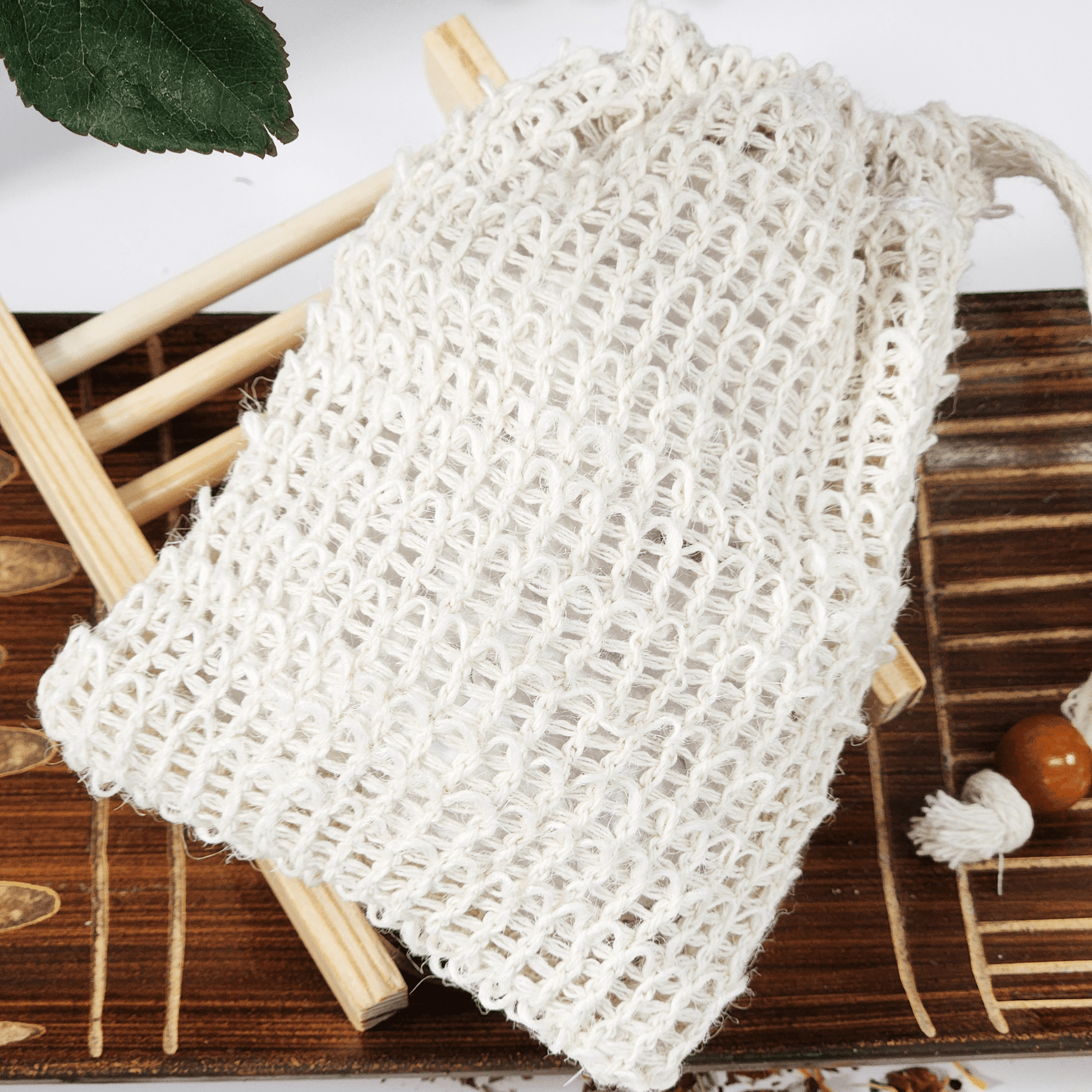 JOSSPURE soap saver and sisal bag for soap on wooden surface with green leaf background